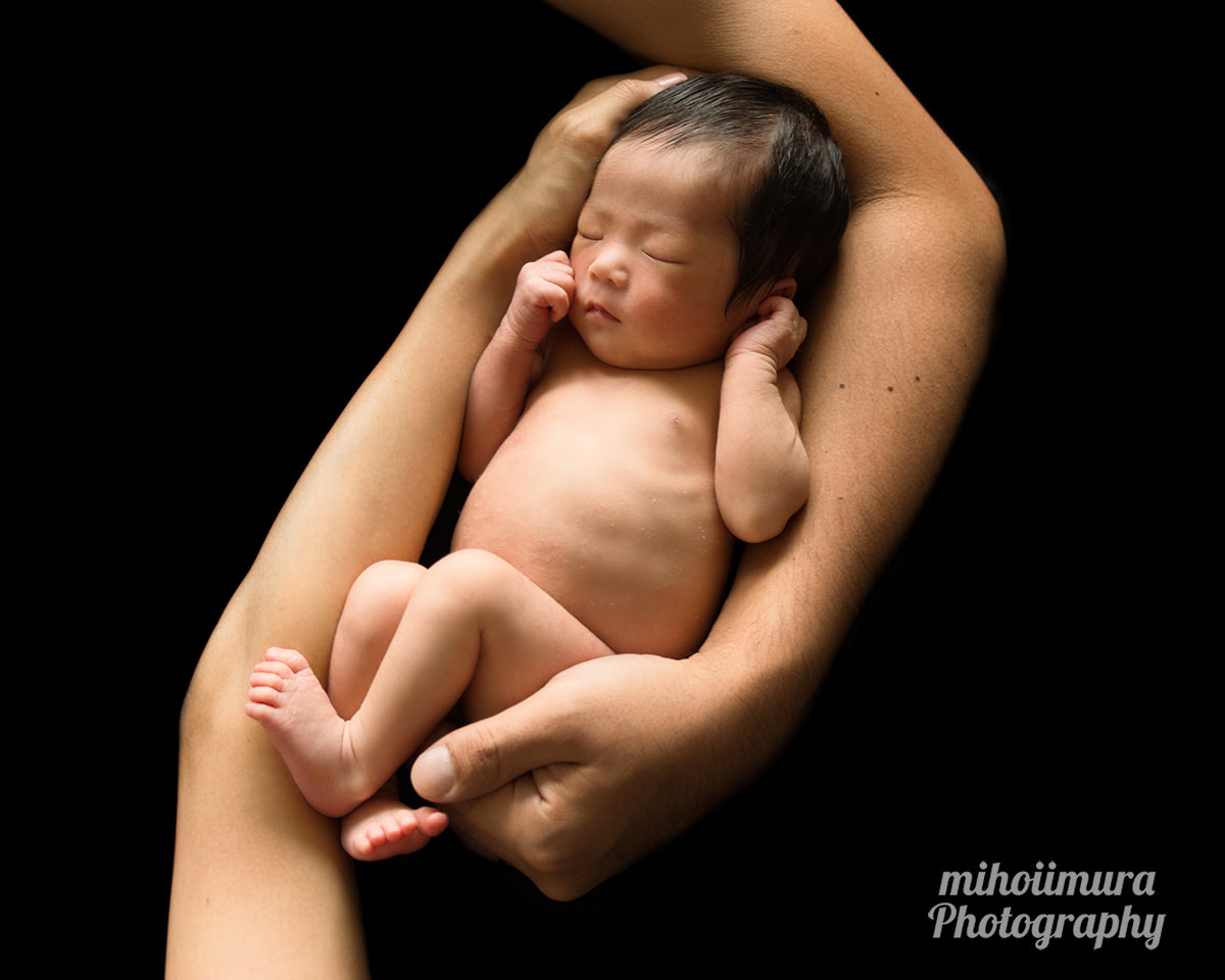 新生児がパパとママの腕に抱えられ裸で寝ている　