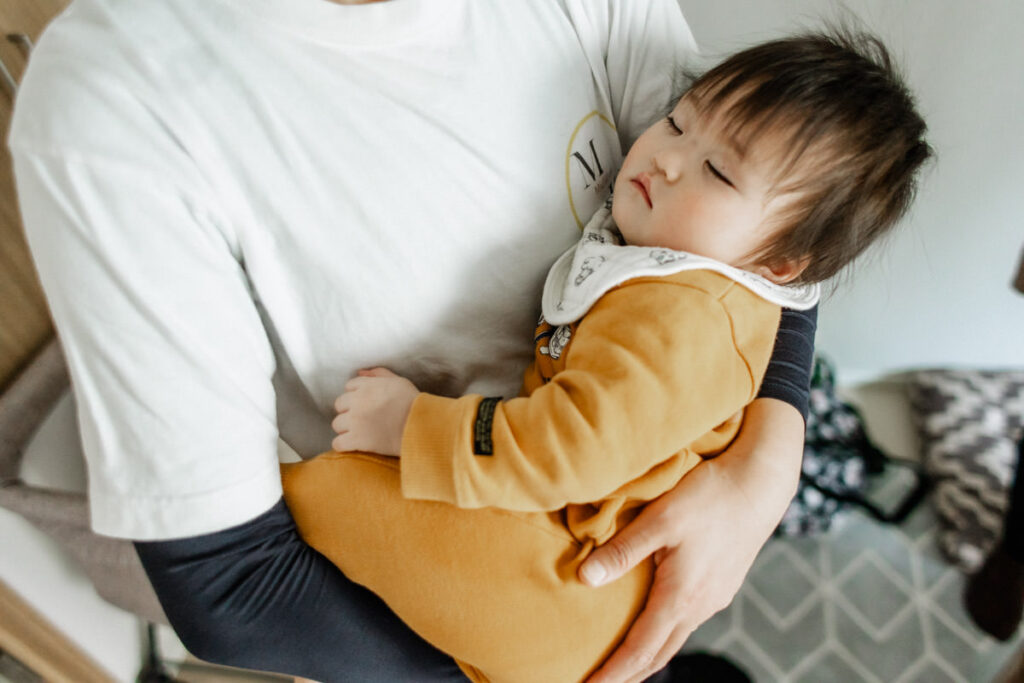 infant sleeping in the arms of mid-wife