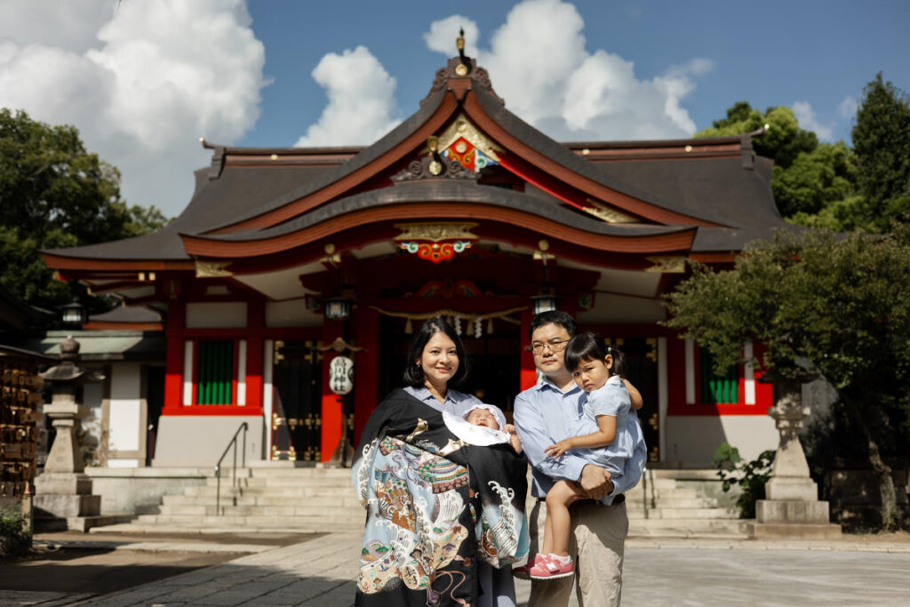 品川神社朱塗りの本殿を前にお宮参りの記念写真