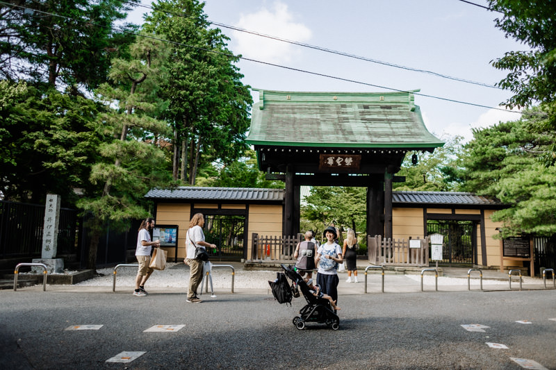 A mother with her child in a stroller standing in front of Gotokuji Temple.