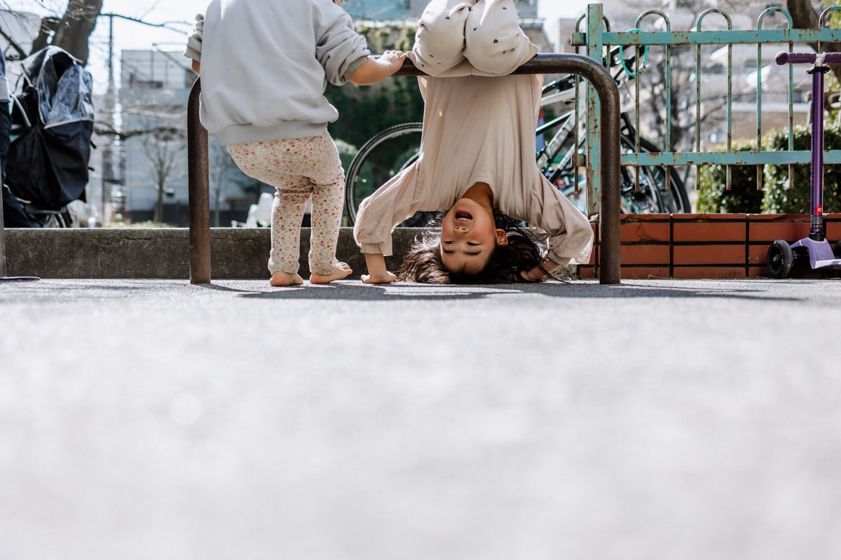 車止めを鉄棒のように使って遊んでいる子ども